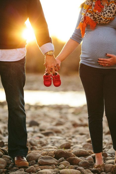 Sesión de fotos de maternidad papás sosteniendo los zapatos del bebé 