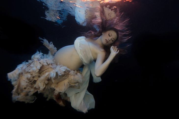 sesión de fotos de maternidad chica bajo el agua mostrando su vientre 