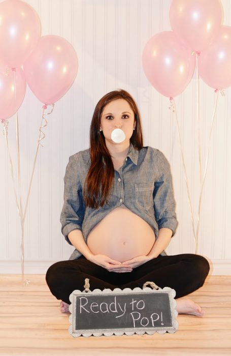 Sesión de fotos de maternidad chica sosteniendo su vientre y mascando chicle 