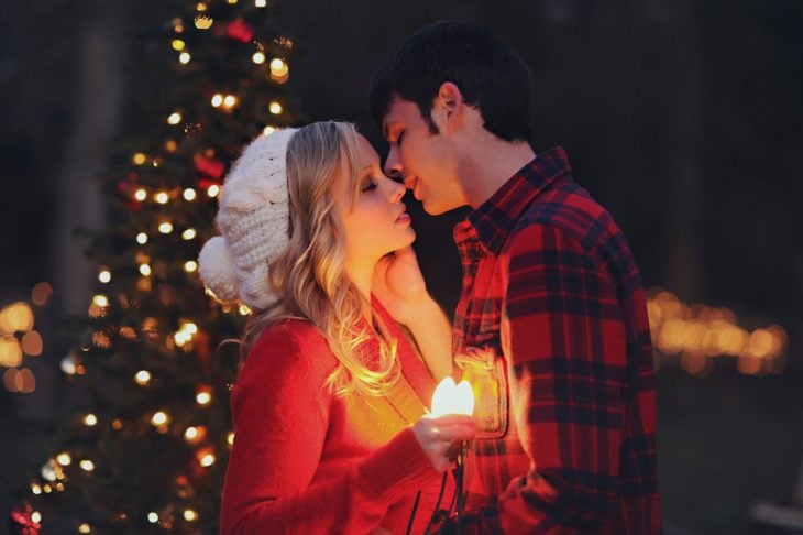 Pareja de novios besándose mientras sostienen una vela 