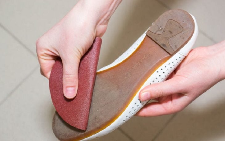 mujer frotando suela de zapato con lija