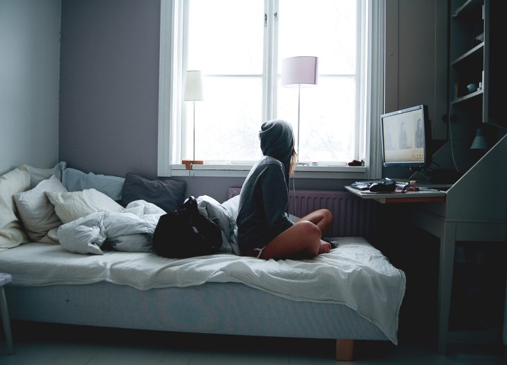 Chica sentada en la cama viendo la televisión 