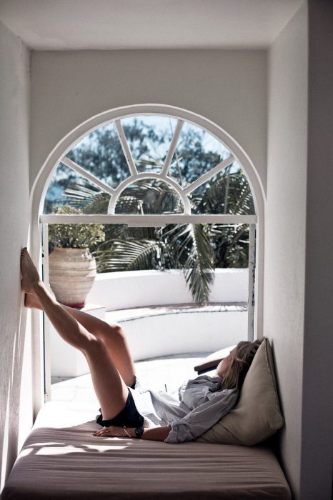 Chica recostada en un sofá frente a la ventana