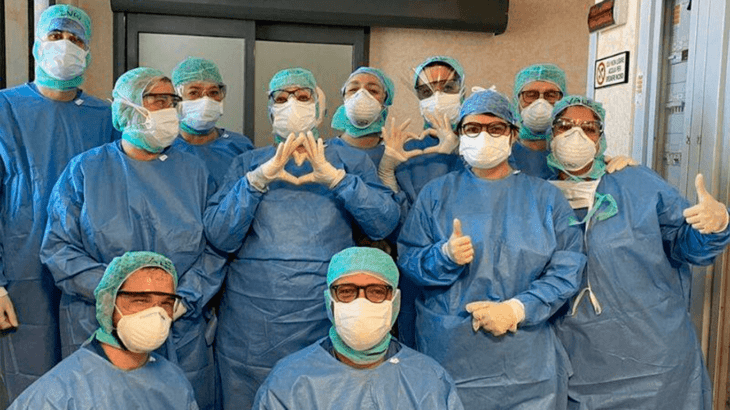 Grupo de enfermeros haciendo señas con sus maos en forma de corazón y bienestar para mostrar su amor por su trabajo