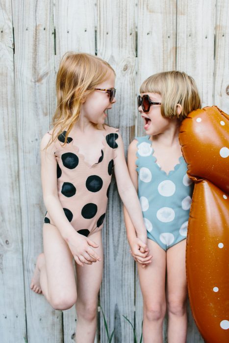 Niñas en traje de baño tomadas de las manos 