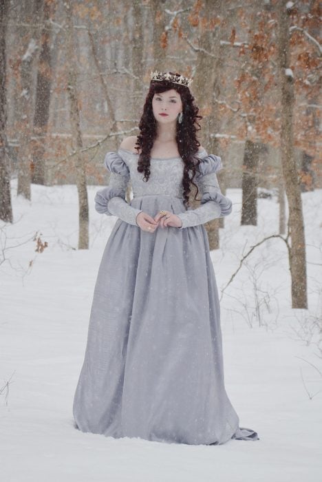 Chica usando un vestido de color lila mientras está parada en la nieve 