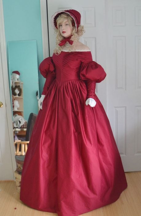 Chica usando un vestido rojo medieval con un sombrero a juego 