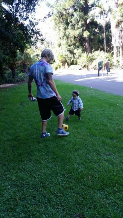 Hombre jugando con un niño a la pelota, ambos con la enfermedad de Treacher Collins