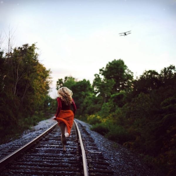 Chica corriendo a través de las vías del tren 