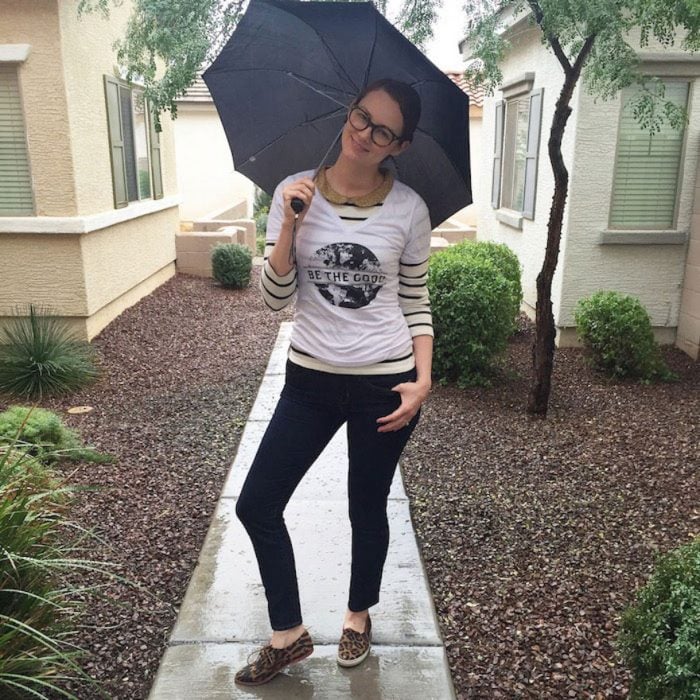 Chica sosteniendo una sombrilla mientras está parada bajo la lluvia posando para una foto 
