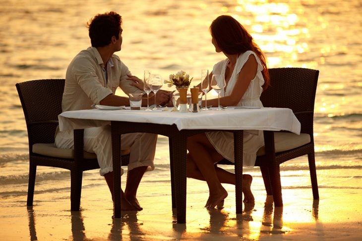 Pareja teniendo una cena romántica a la orilla del mar