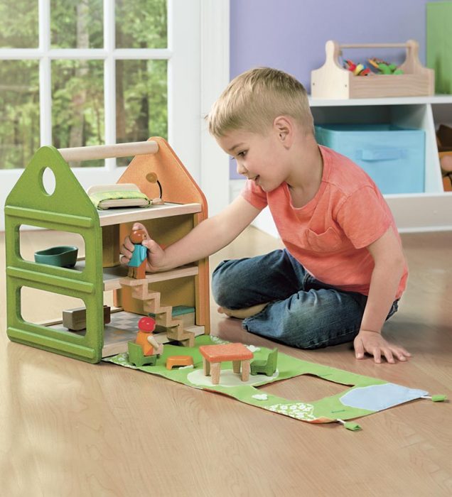 Niño jugando con una casa de muñecas