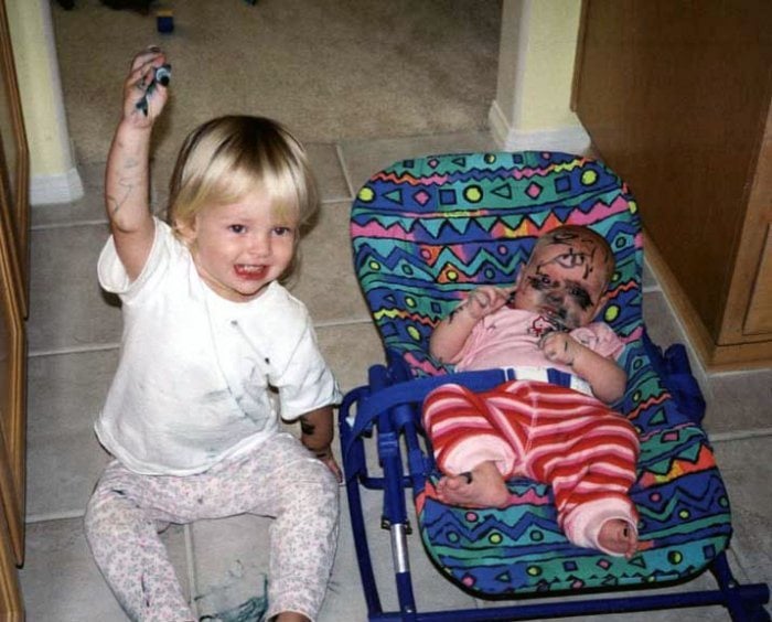 niño con un plumón pintando la cara de su hermana 