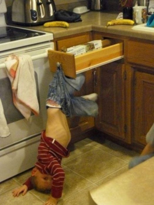 Niño colgando de sus pantalones desde un cajón 