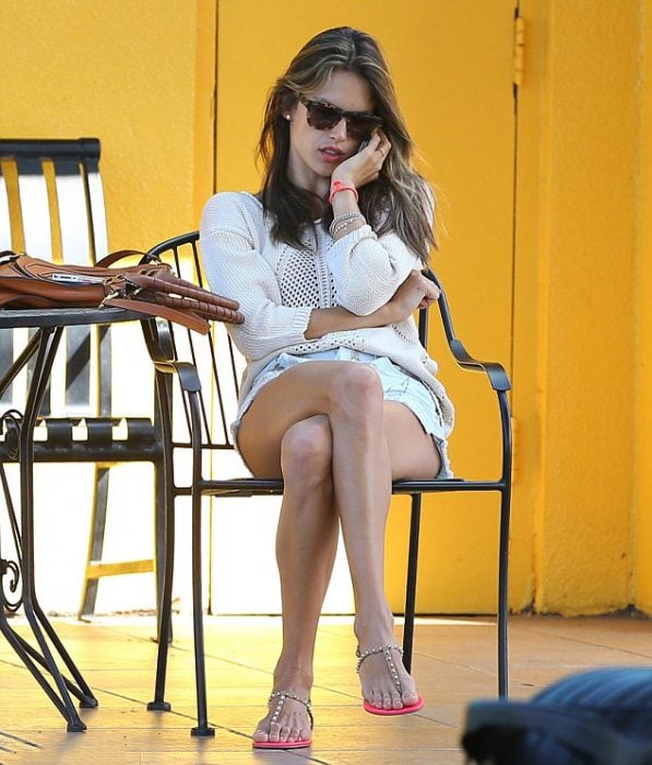 Chica sentada en una cafetería con los pies cruzados 