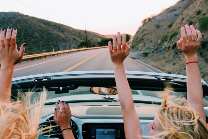 Chicas en un auto convertible en la carretera 