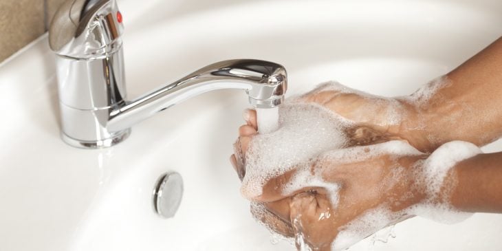 Chica lavando sus manos en un lavabo con jabón 