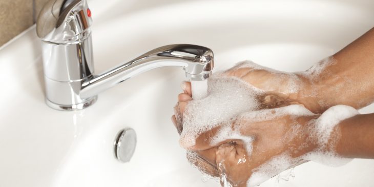 Chica lavando sus manos en un lavabo con jabón 