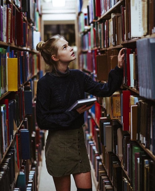 Chica en una biblioteca eligiendo libros 