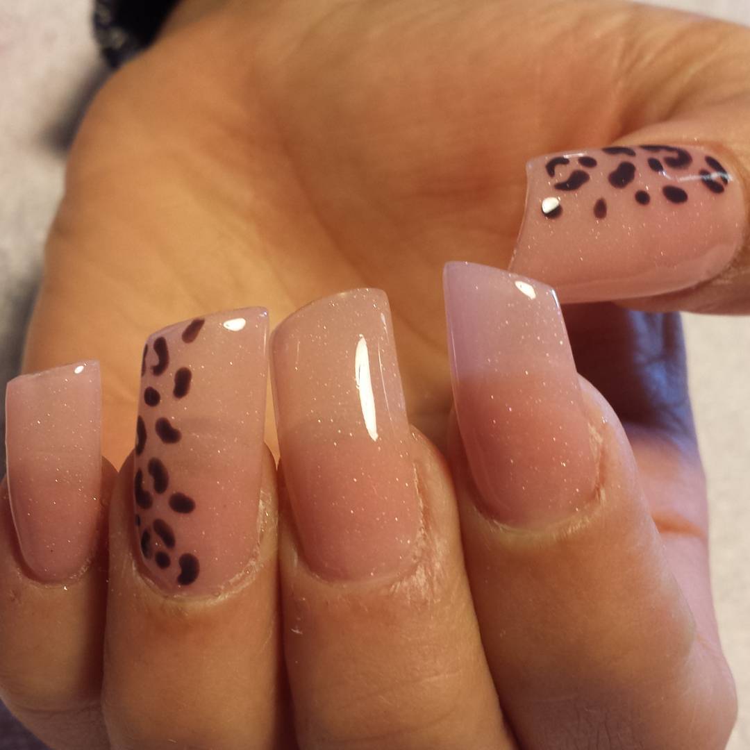 Tipo de uñas con forma de lipstick en color nude con manchas de leopardo.