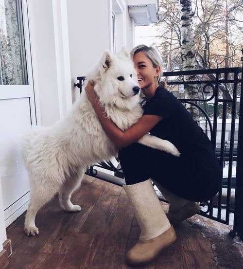 Chica abrazando a un perro en la entrada de su casa 