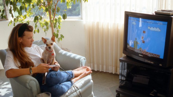 Chica jugando video juegos junto con un cachorro 