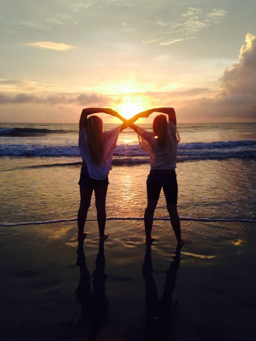 amigas haciendo signo infinito en la playa