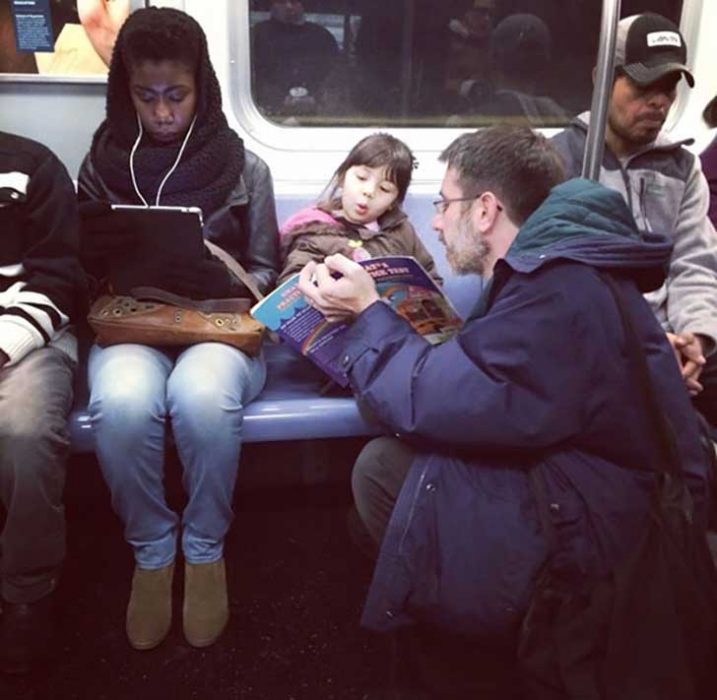 papá leyendo un cuento a hija en el metro