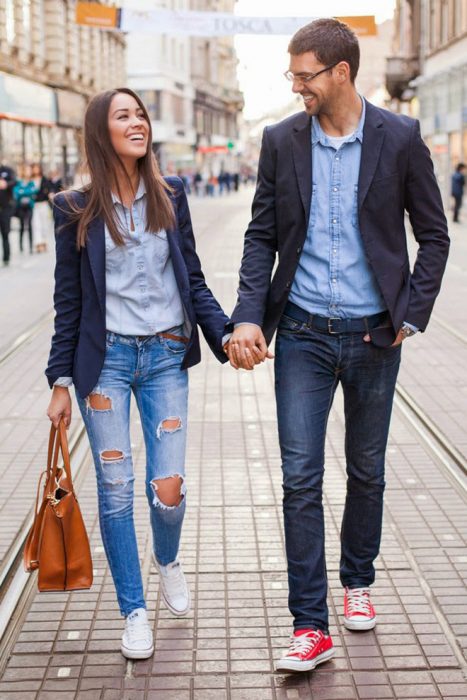 Pareja de novios vestidos igual caminando por las calles tomados de las manos 