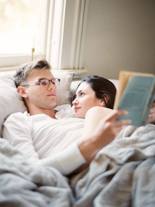 Pareja de novios leyendo un libro mientras ambos están recostados 