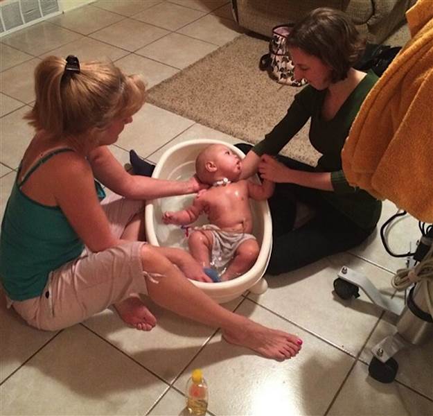 Cori e hija bañando a un bebé