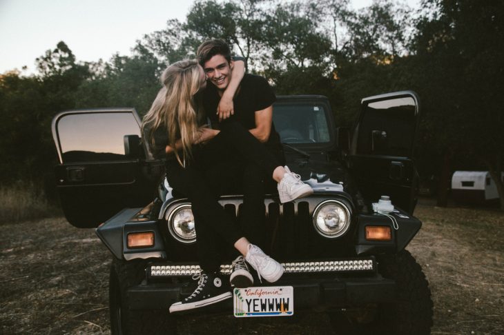 Pareja feliz en el cofre de un carro 