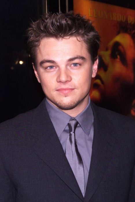 Leonardo DiCaprio usando un traje azul y una camisa morada en una red carpet del año 2000