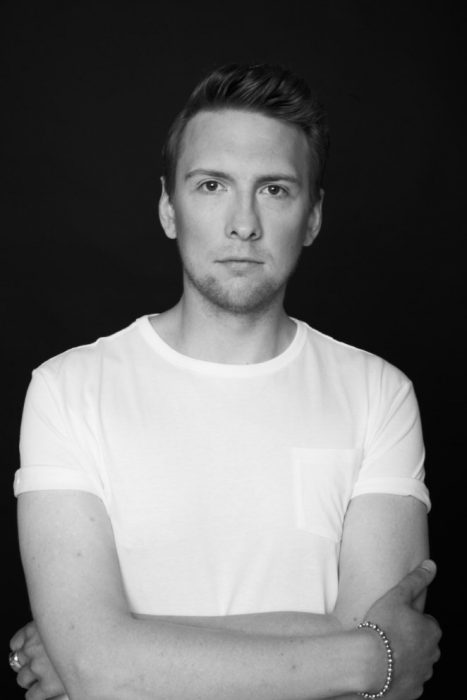 comediante Joe Lycett usando una camisa blanca durante una sesión de fotos 