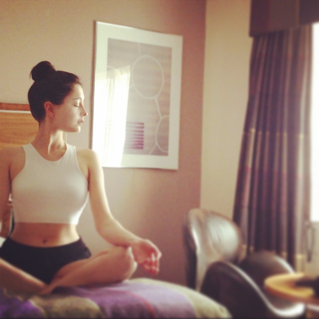 Amalia Ulman tomandose una fotografía mientras practica yoga sentada en la cama 
