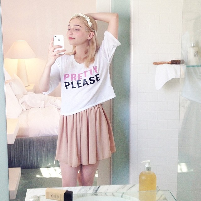 Amalia Ulman vestida con falda rosa y blusa blanca tomándose una fotografía frente a un espejo 