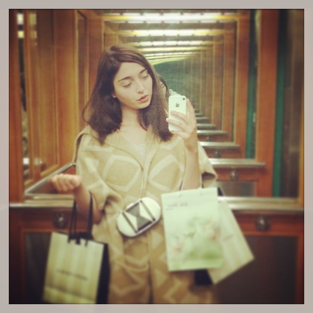 Amalia Ulman tomándose una selfie frente a un espejo mientras carga bolsas en sus manos 