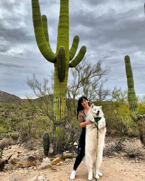 Lauren Urasek sosteniendo a un perro en un desierto