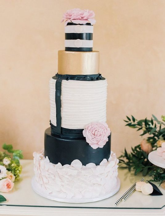 Pastel de bodas en color blanco, negro y dorado con flores en color rosa bebé 