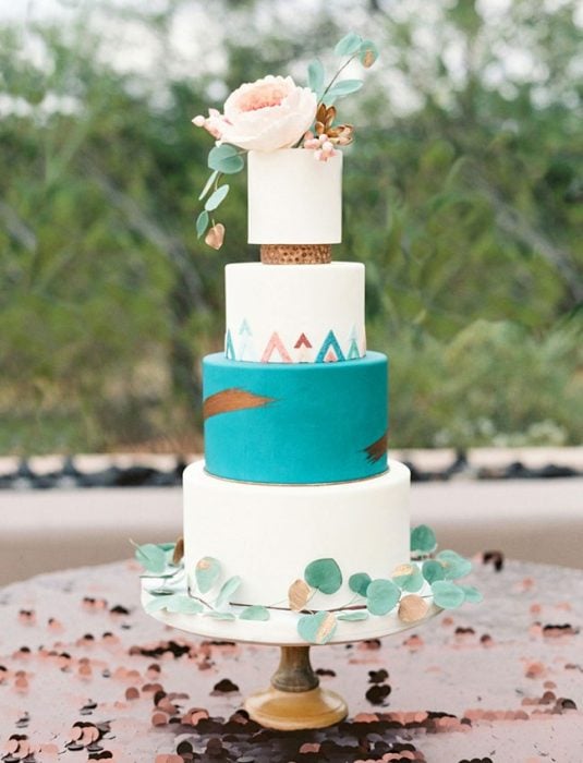 Pastel de bodas en color blanco con azul y en la punta flores de color blanco 