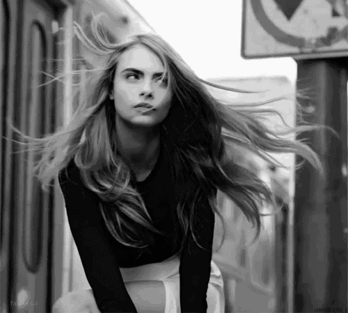 GIF Cara Delevinge posando para una fotografía mientra el viento está en su cara 