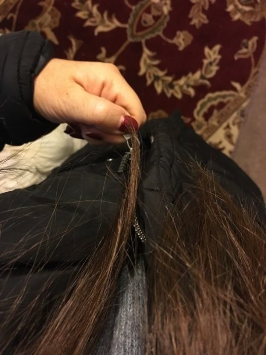 Chica con el cabello largo atorado en el ziper de una chamarra 