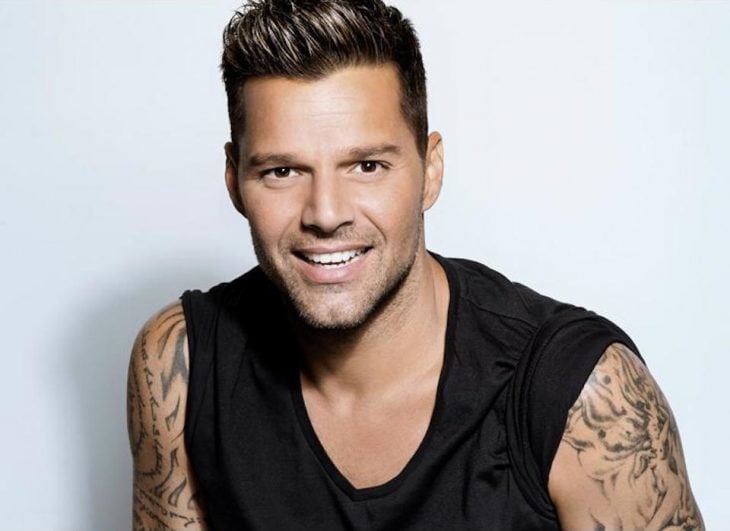 Cantante Ricky Martin usando una camisa negra y sonriendo en una sesión de fotos 