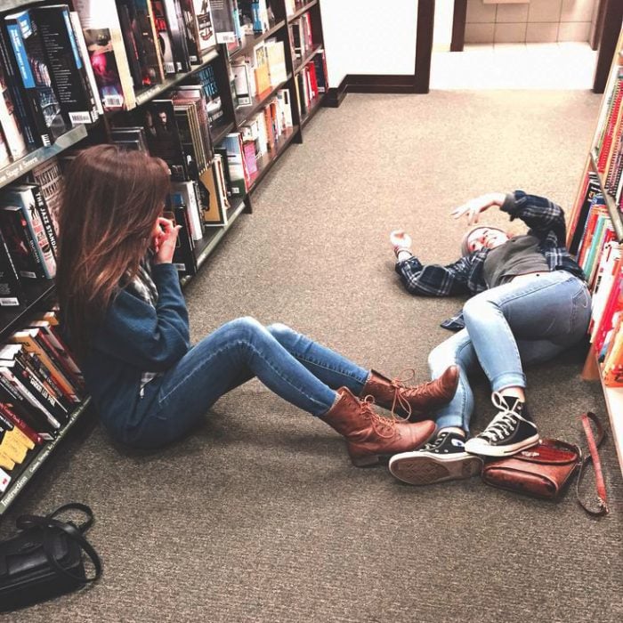 Chicas en una biblioteca recostadas en el suelo 