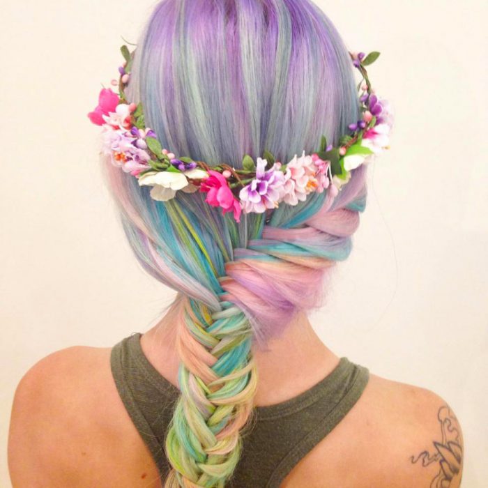 Chica con el cabello de colores y una trenza cola de pez adornada con flores 