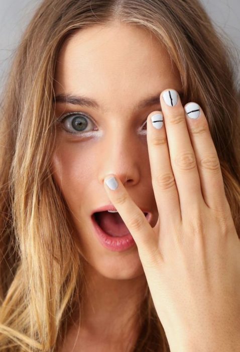 Uñas con diseños minimalistas en color blanco con lineas en color negro 