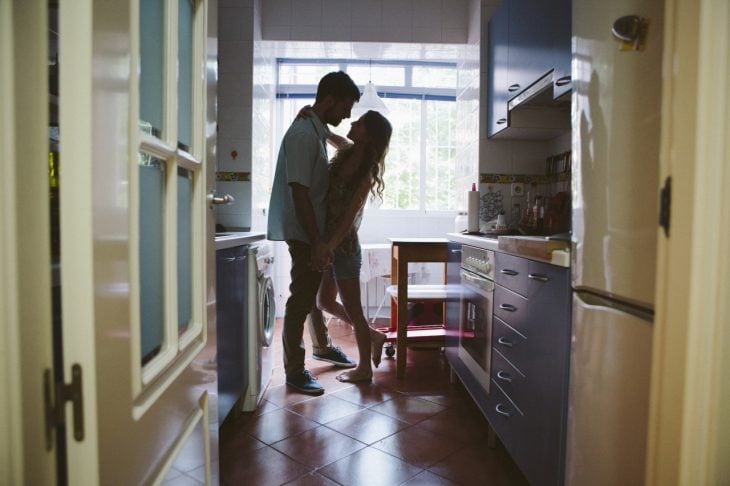 Pareja de novios en la cocina besándose 