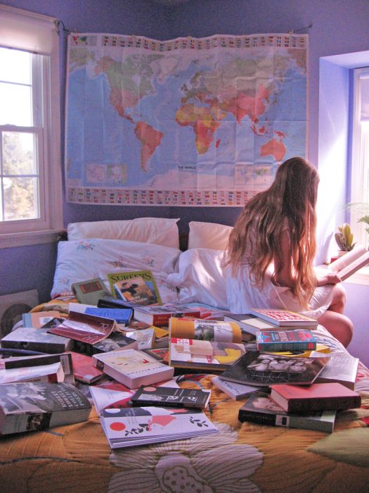 mujer sentada cama libros leyendo