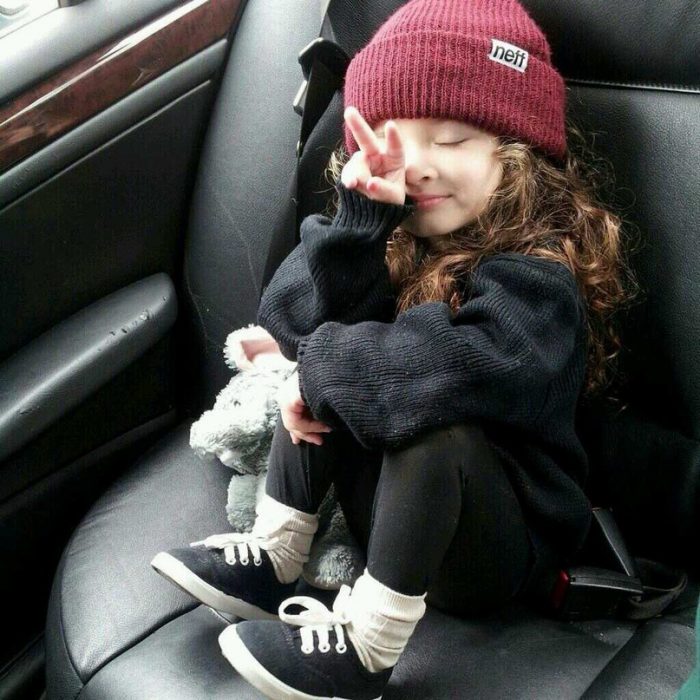 niña con gorra sentada señal amor y paz