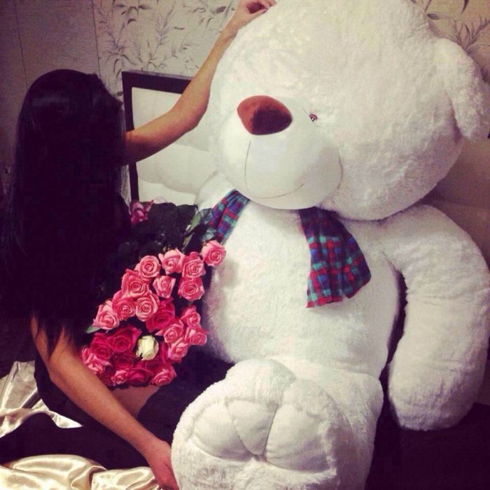 chica con oso de peluche gigante y flores